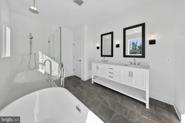 a spacious bathroom with a double vanity sink a mirror and a bathtub