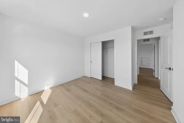 a view of an empty room with wooden floor and a bathroom