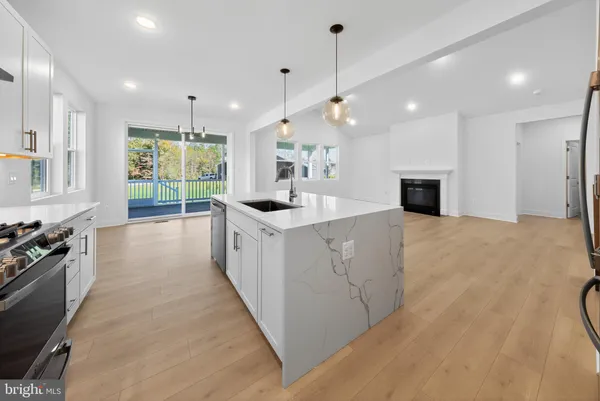 a large kitchen with kitchen island a large counter top a sink stainless steel appliances and cabinets
