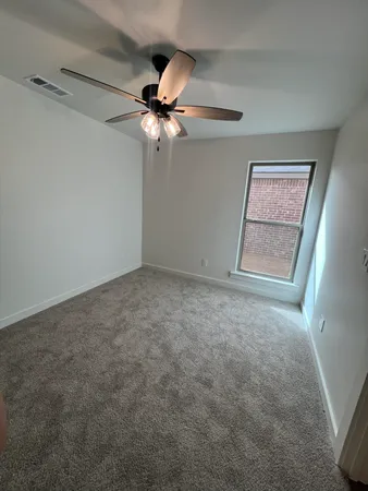 an empty room with windows and fan
