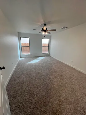 an empty room with a chandelier fan and windows