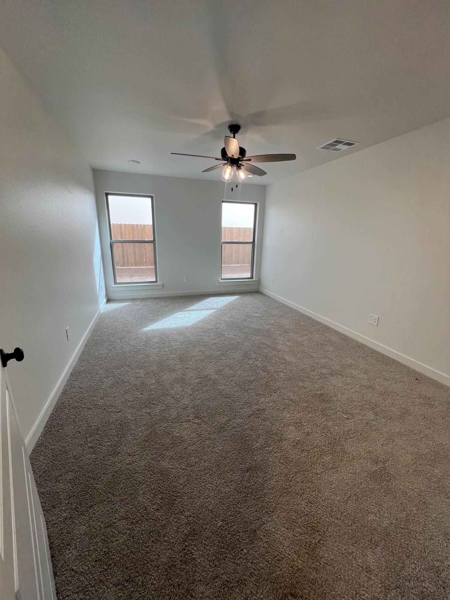 3105 140th Street Lubbock, TX 79423 - Photo 18 of 23 an empty room with a chandelier fan and windows