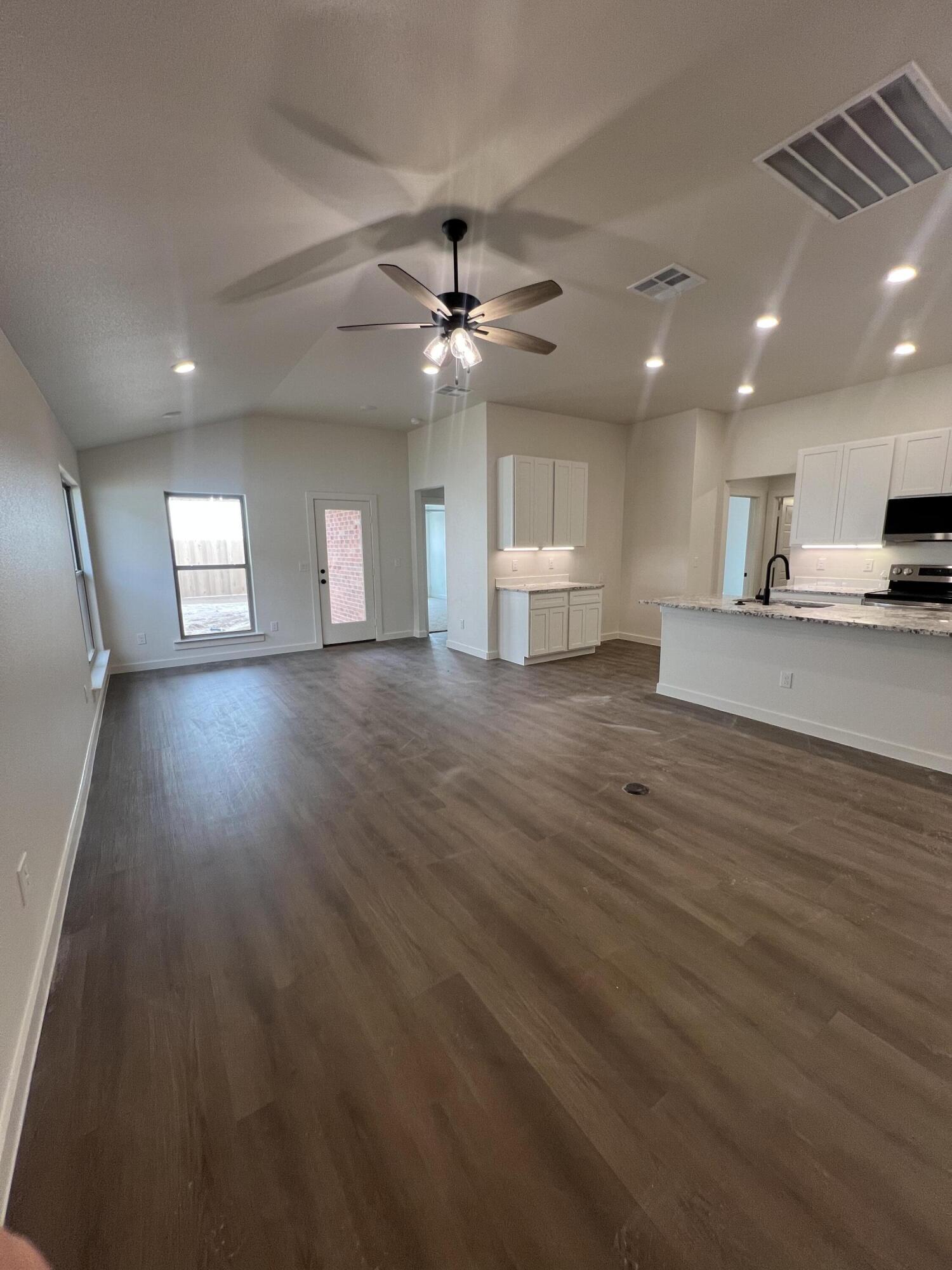 3105 140th Street Lubbock, TX 79423 - Photo 6 of 23 an empty room with wooden floor ceiling fan and windows