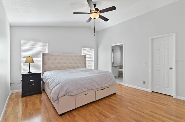 a bedroom with a bed and dresser with wooden floor