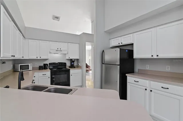 a kitchen with granite countertop a refrigerator and a stove top oven