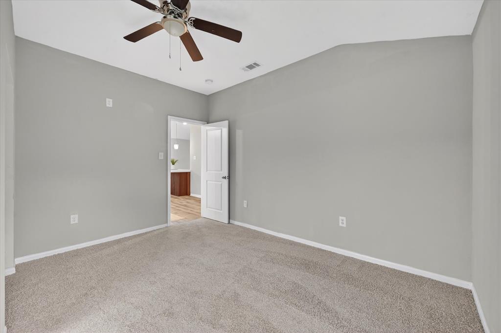 538 Pemberton Hill Road Dallas, TX 75217 - Photo 13 of 31 Spacious room featuring neutral carpeting, light gray wall paint, and a ceiling fan with wood-finish blades