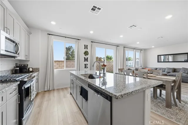 a kitchen with granite countertop stainless steel appliances a table and chairs in it