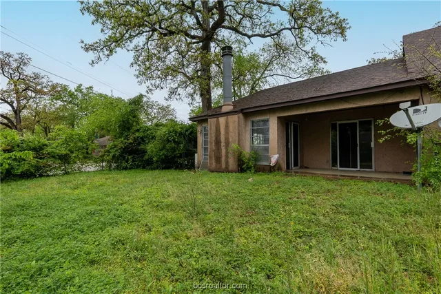 a view of a backyard with potted plants and large tree