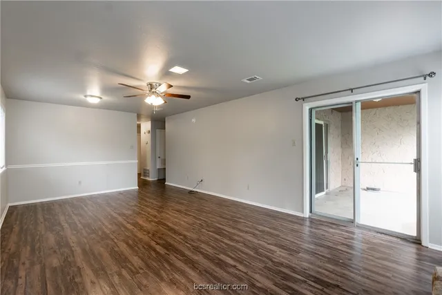 an empty room with wooden floor and a ceiling fan