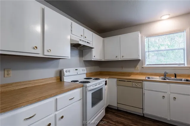a kitchen with granite countertop white cabinets and white appliances