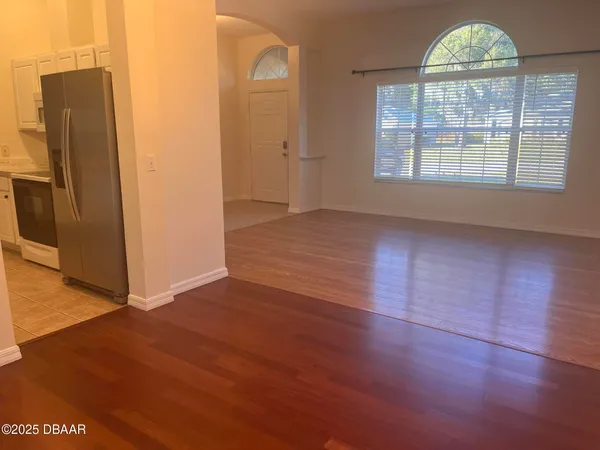an empty room with wooden floor cabinet and windows