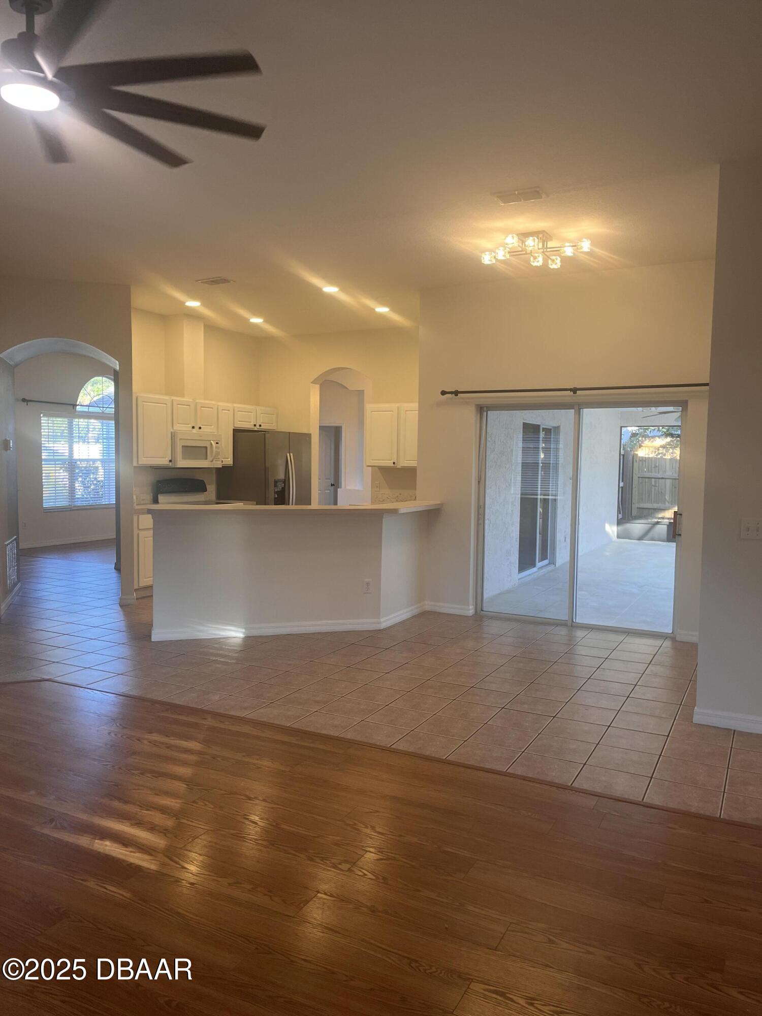 612 John Thomas Avenue DeLand, FL 32724 - Photo 6 of 11 a view of a living room a kitchen with stainless steel appliances wooden floor and chandelier