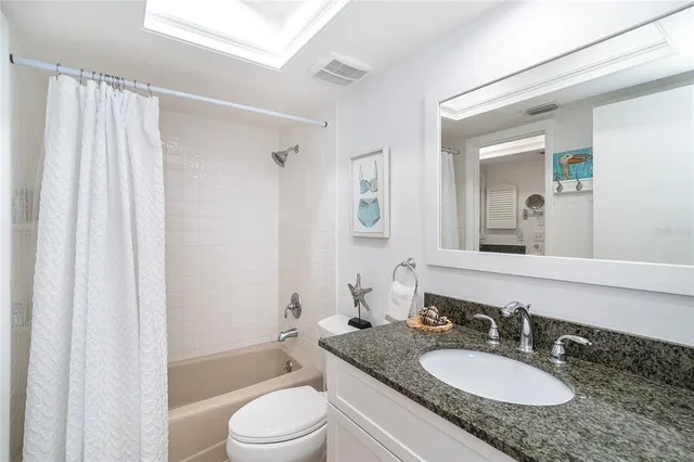 a bathroom with a granite countertop sink toilet a mirror a bathtub and shower