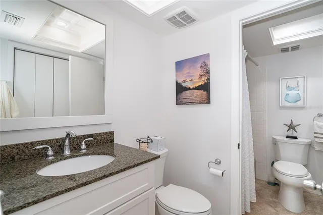 a bathroom with a granite countertop toilet sink and mirror