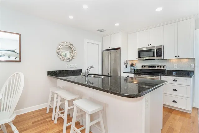 a kitchen with stainless steel appliances granite countertop a refrigerator a stove a sink and white cabinets