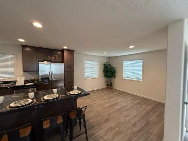 a kitchen with sink refrigerator dining table and chairs