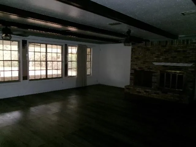 a view of an empty room with wooden floor and a floor to ceiling window