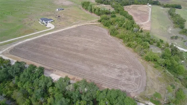 an aerial view of residential houses with outdoor space and trees
