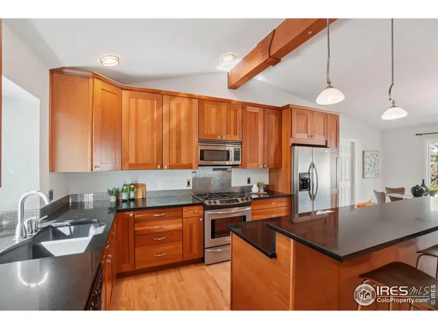 a kitchen with kitchen island granite countertop a sink a counter top space appliances and cabinets