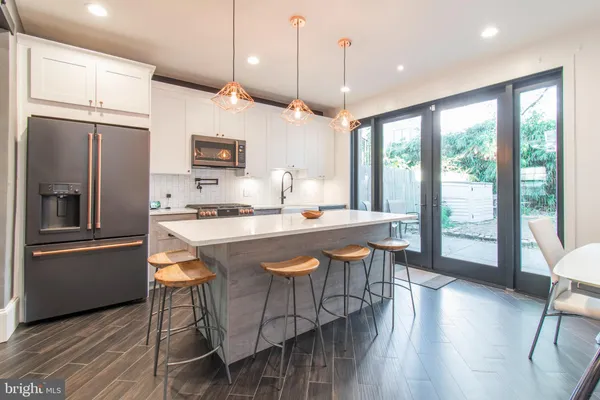 a kitchen with stainless steel appliances granite countertop a stove a refrigerator a sink a dining table and chairs with wooden floor