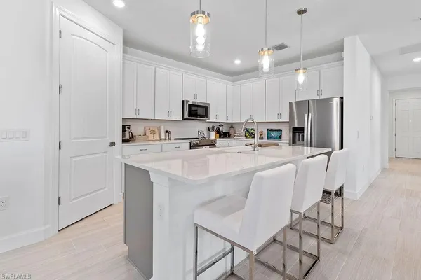 a kitchen with kitchen island microwave stove refrigerator and white cabinets