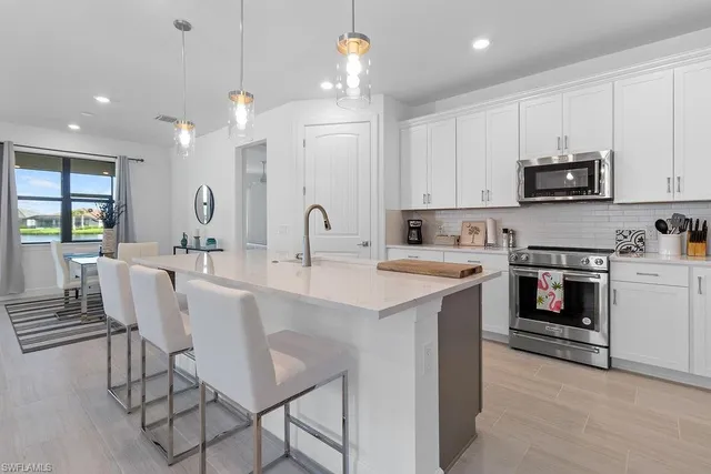 a kitchen with stainless steel appliances a stove a sink a microwave a center island and a cabinets