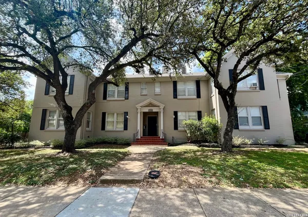 a front view of a house with a yard and tree