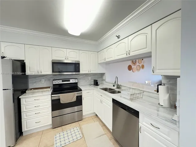 a kitchen with granite countertop a sink stainless steel appliances and white cabinets