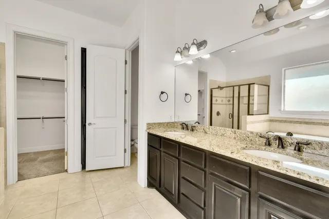 a bathroom with a granite countertop sink two mirror and a shower