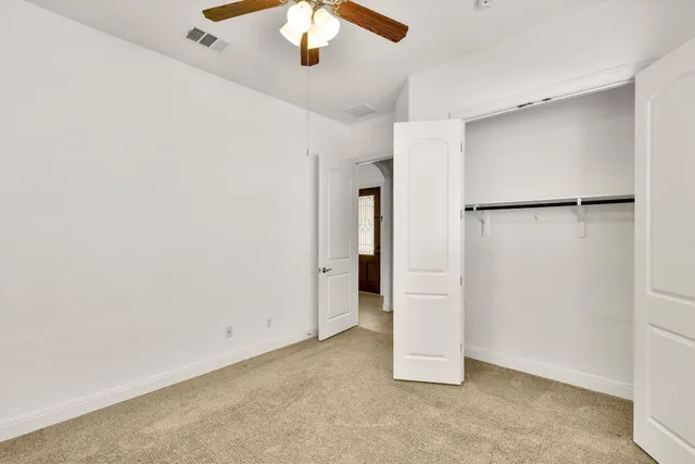 an empty room with closet and a chandelier fan