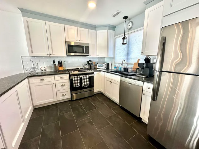a kitchen with a sink a refrigerator a microwave and cabinets
