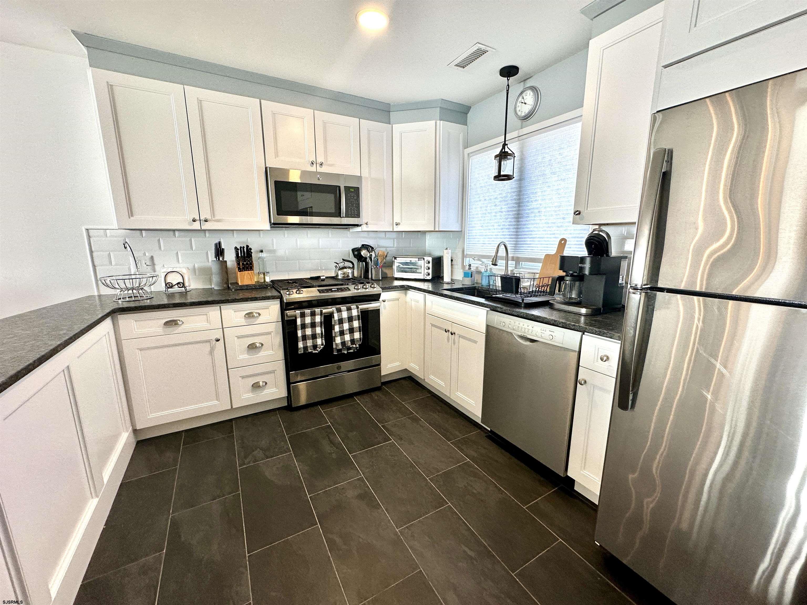 612 East Brigantine Avenue, Unit 612 Brigantine, NJ 08203 - Photo 6 of 29 a kitchen with a sink a refrigerator a microwave and cabinets