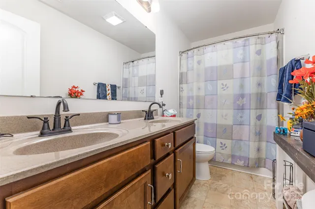 a bathroom with a granite countertop sink a toilet and shower