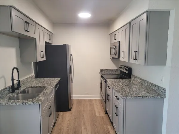 a kitchen with stainless steel appliances granite countertop a sink stove and refrigerator