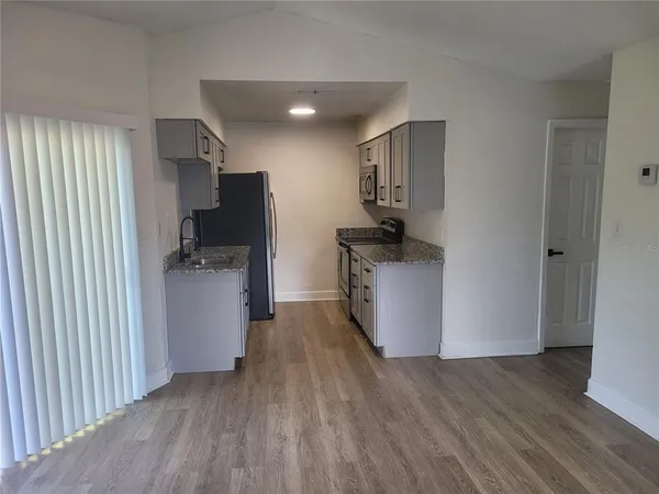 a view of a kitchen with a sink refrigerator and wooden floor