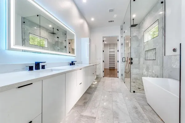 a large white bathroom with a large tub a sink shower and mirror