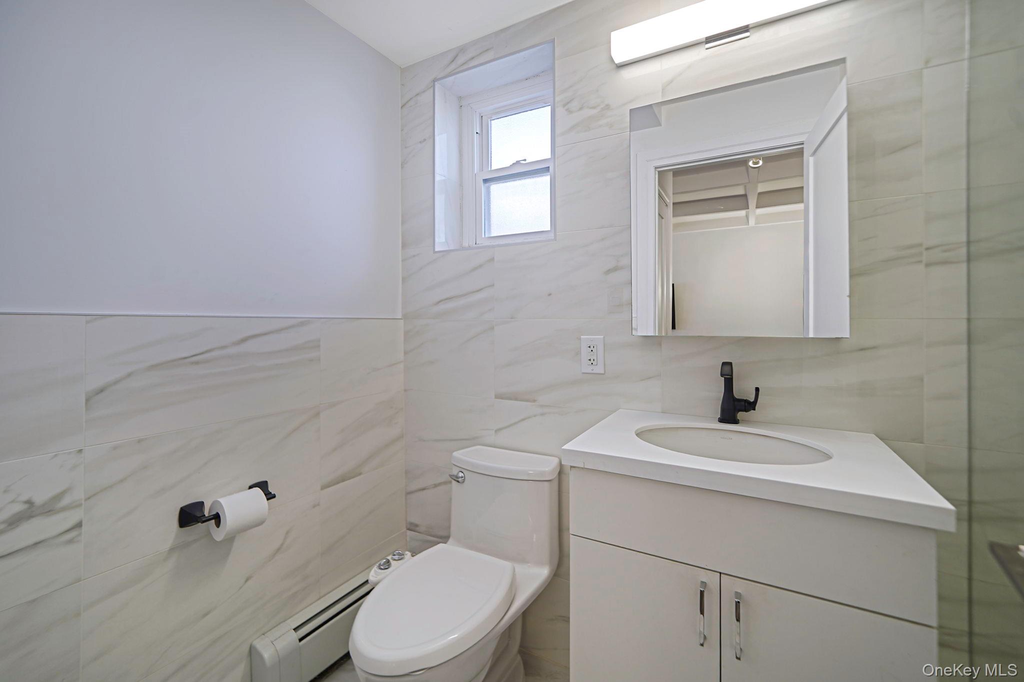 144-66 Village Road, Unit 75D Queens, NY 11435 - Photo 8 of 19 a bathroom with a sink a toilet and a mirror