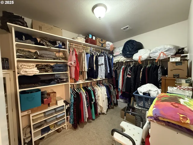 a view of walk in closet with clothes and shoes