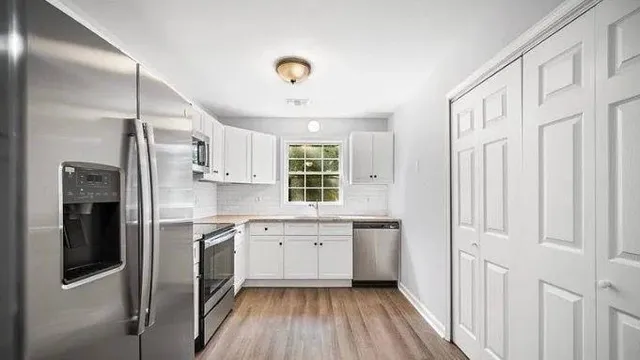 a kitchen with white cabinets and wooden floor