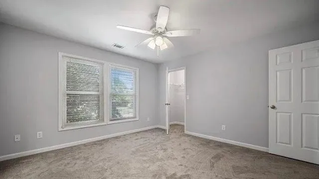 an empty room with fan and windows
