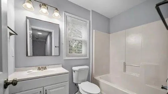 a bathroom with a toilet sink vanity tub and mirror