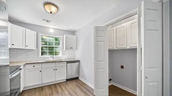 a kitchen with white cabinets and wooden floor