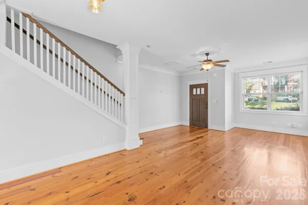 a view of an empty room with wooden floor and a window