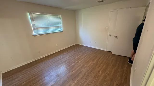 an empty room with wooden floor and windows