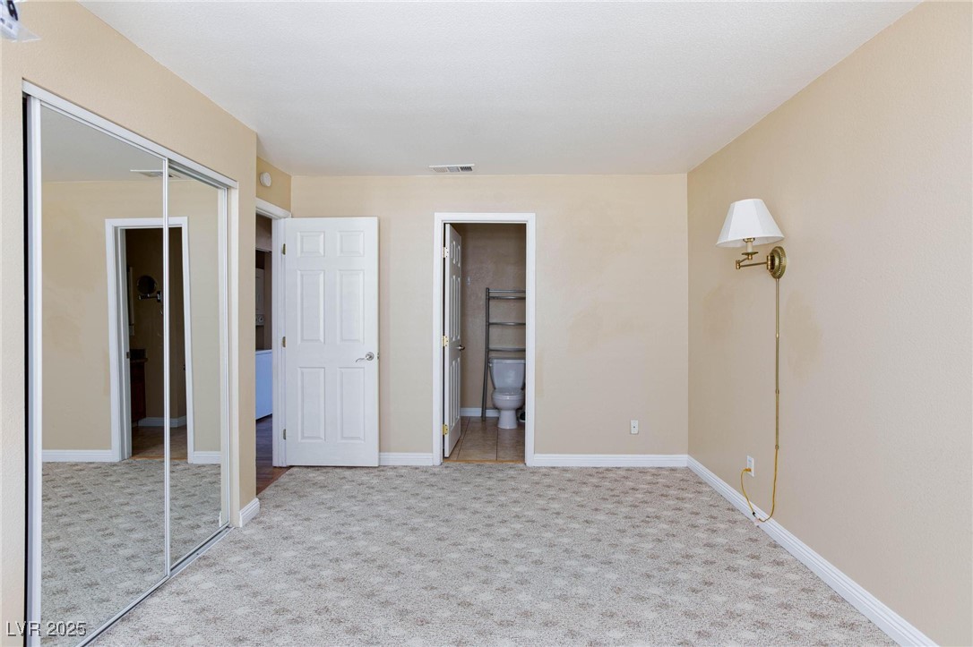 7300 West Pirates Cove Road, Unit 2038 Las Vegas, NV 89145 - Photo 13 of 26 Unfurnished bedroom featuring a closet, light colored carpet, and connected bathroom