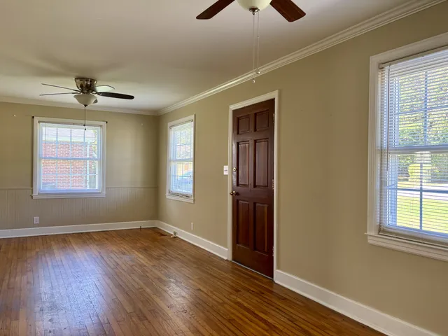 a view of empty room with wooden floor and fan