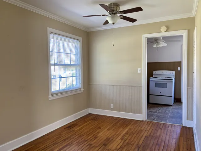 a view of an empty room with a window and wooden floor