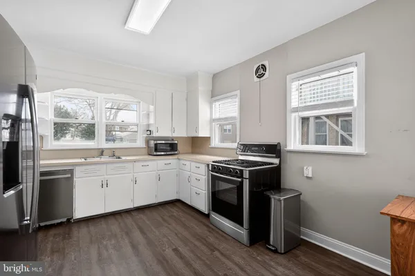 a kitchen with stainless steel appliances granite countertop hardwood floor sink stove and wooden cabinets