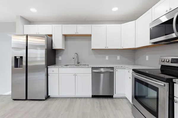 a kitchen with cabinets stainless steel appliances a sink and wooden floor