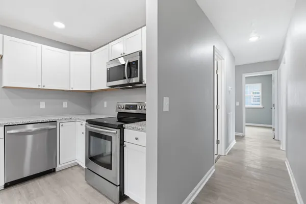 a kitchen with stainless steel appliances granite countertop grey cabinets a stove a microwave and a refrigerator